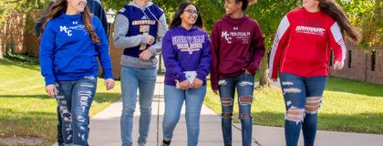 Two male students and 4 female students walking outside.