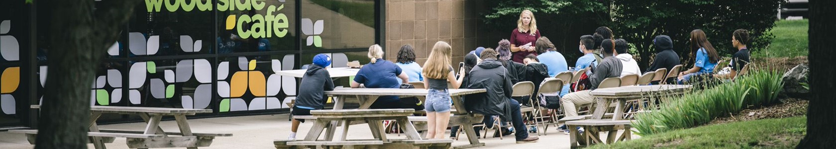 students on picnic tables outside of the woodside cafe