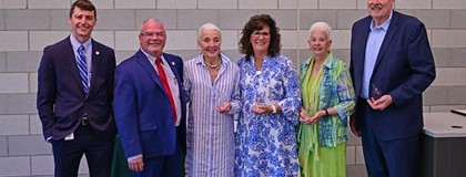 MCC 2024 Distinguished Service Award recipients holding awards in front of brick wall.