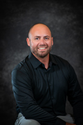 Professional photo of Taylor Logan wearing a black button down shirt in front of a gray background.