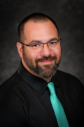 Professional photo of Raymond Ruiter wearing a black button down and blue tie.