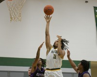 MCC Men's Basketball player jumps to take a shot while two opposing players attemot to block/catch the rebound. 