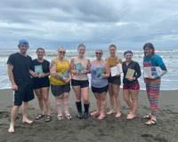 Students and staff who traveled abroad to Costa Rica pose for a photo on the beach with the book, My Life with Sea Turtles.