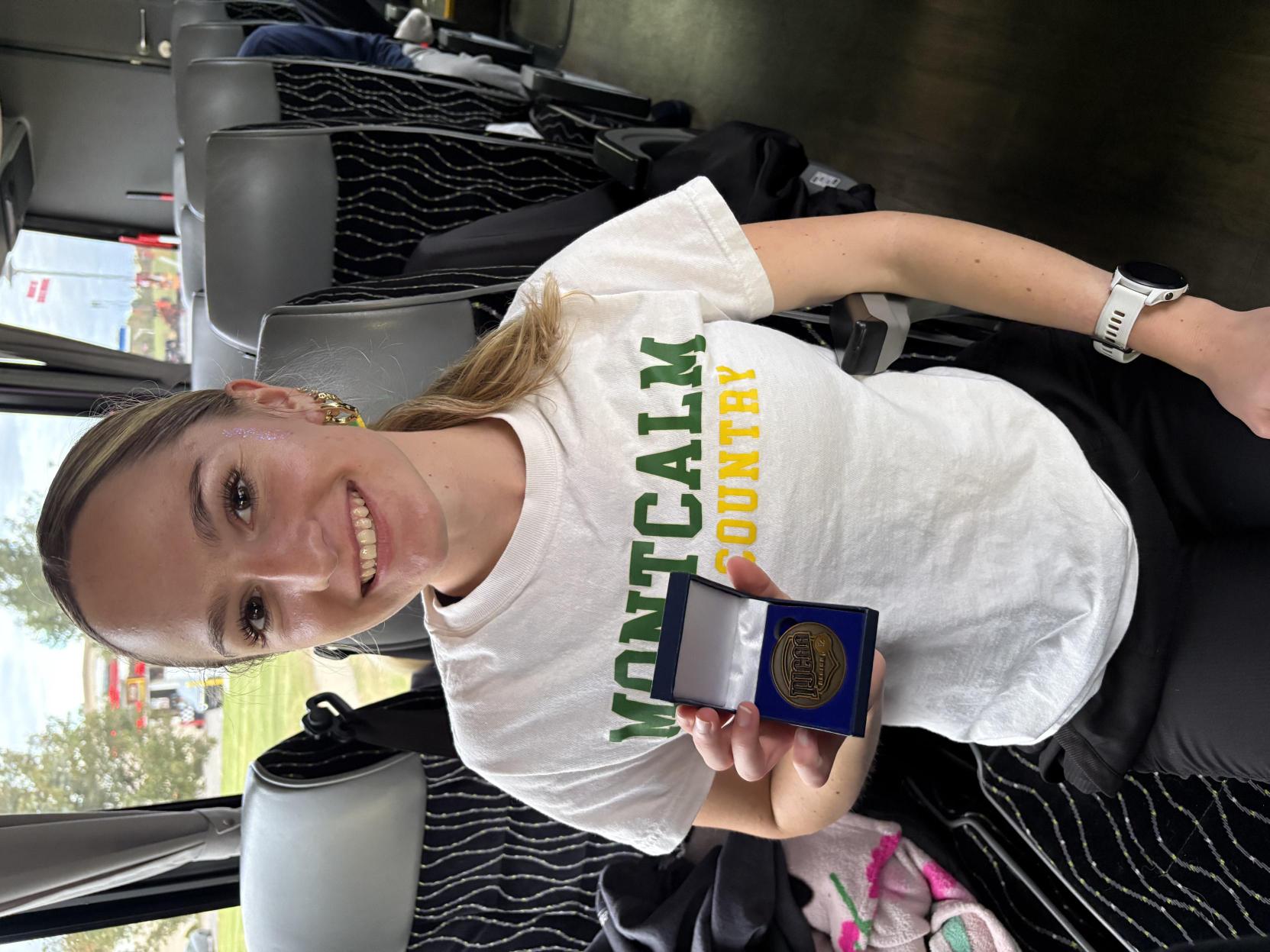 MCC Cross Country runner Abby Davis holds up NJCAA metal.