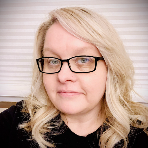 Photo of MCC Success Coach Marlo Tiffany smiling. She wears a black shirt, black glasses and has blonde hair.