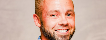 Headshot of Bob Byram smiling and wearing a blue and white checked shirt.