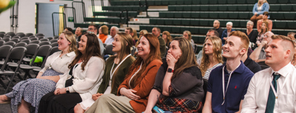 Seven MCC nursing students sitting down and smiling at the stage at their pinning ceremony on May 1, 2025.