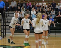 Four MCC women's volleyball players celebrating on the court together.
