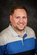 Professional photo of Jonathan Diefenbach wearing a blue and gray striped shirt smiling at the camera.