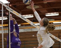 MCC Volleyball player jumping and hitting the volleyball over the net while an opposing player attempts to block the ball.